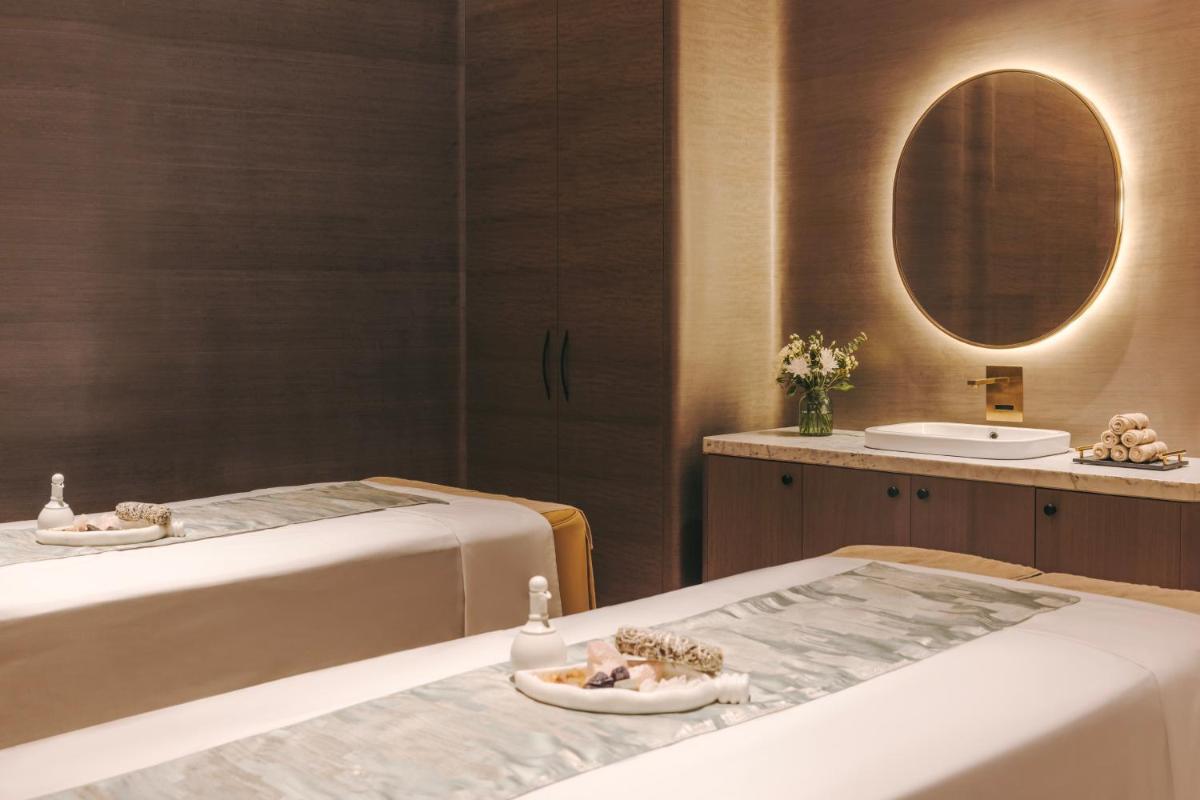 two beds in a room with a mirror and a sink at Fairmont Mumbai in Mumbai