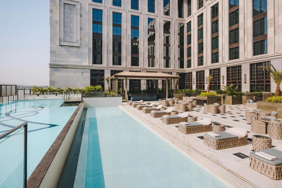 a view of a hotel pool with chairs and tables at Fairmont Mumbai in Mumbai a view of a hotel pool with chairs and tables at Fairmont Mumbai in Mumbai