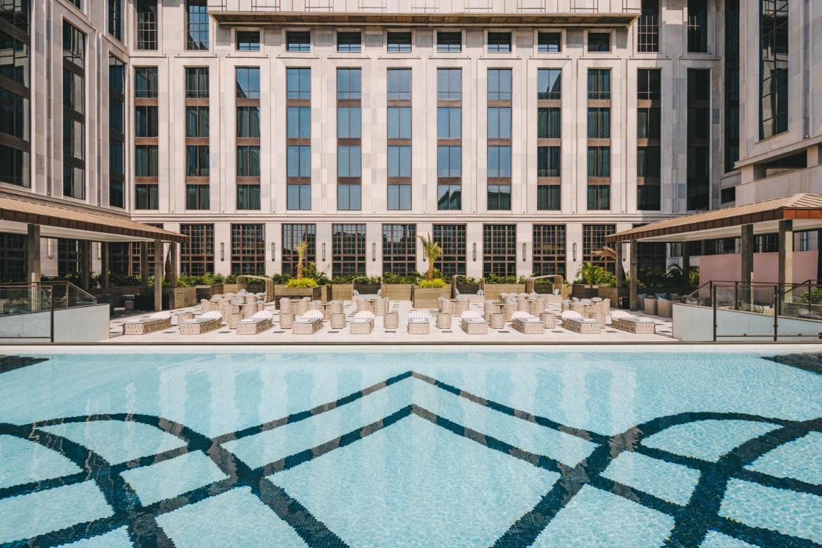 a large swimming pool with chairs and a building at Fairmont Mumbai in Mumbai