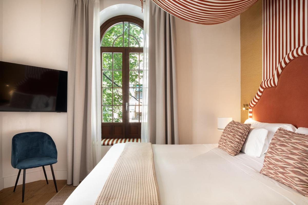 Un dormitorio con una cama grande y una ventana. en Cavalta Boutique Hotel - Small Luxury Hotels, en Sevilla