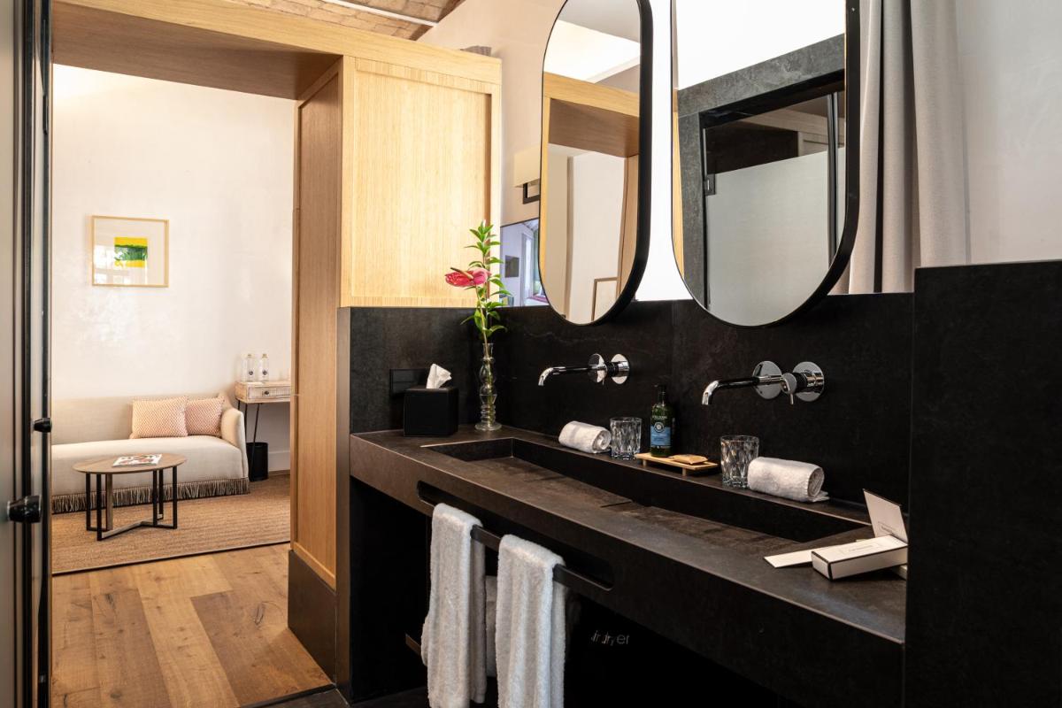 Un baño con lavabo negro y espejos. en Cavalta Boutique Hotel - Small Luxury Hotels, en Sevilla