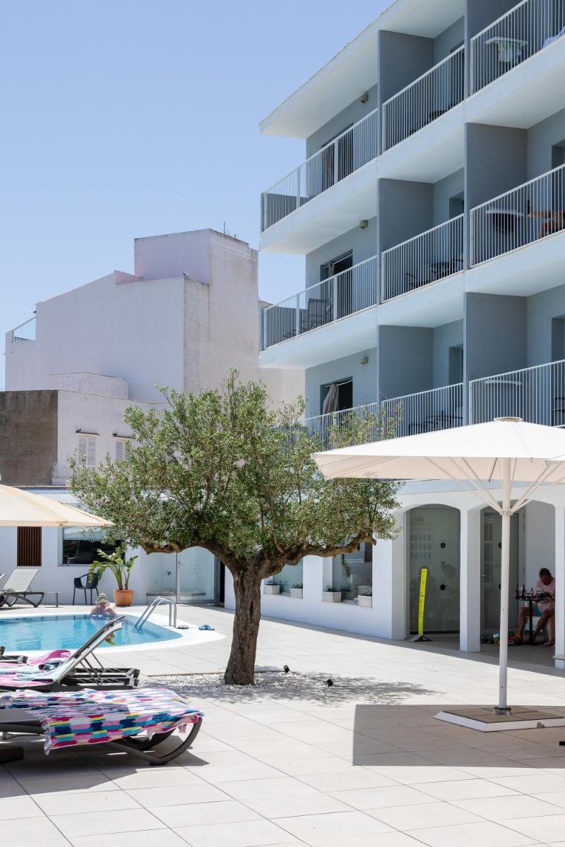 Una piscina con una sombrilla al lado de un edificio. en ARTIEM Carlos - Adults Only, en Es Castell