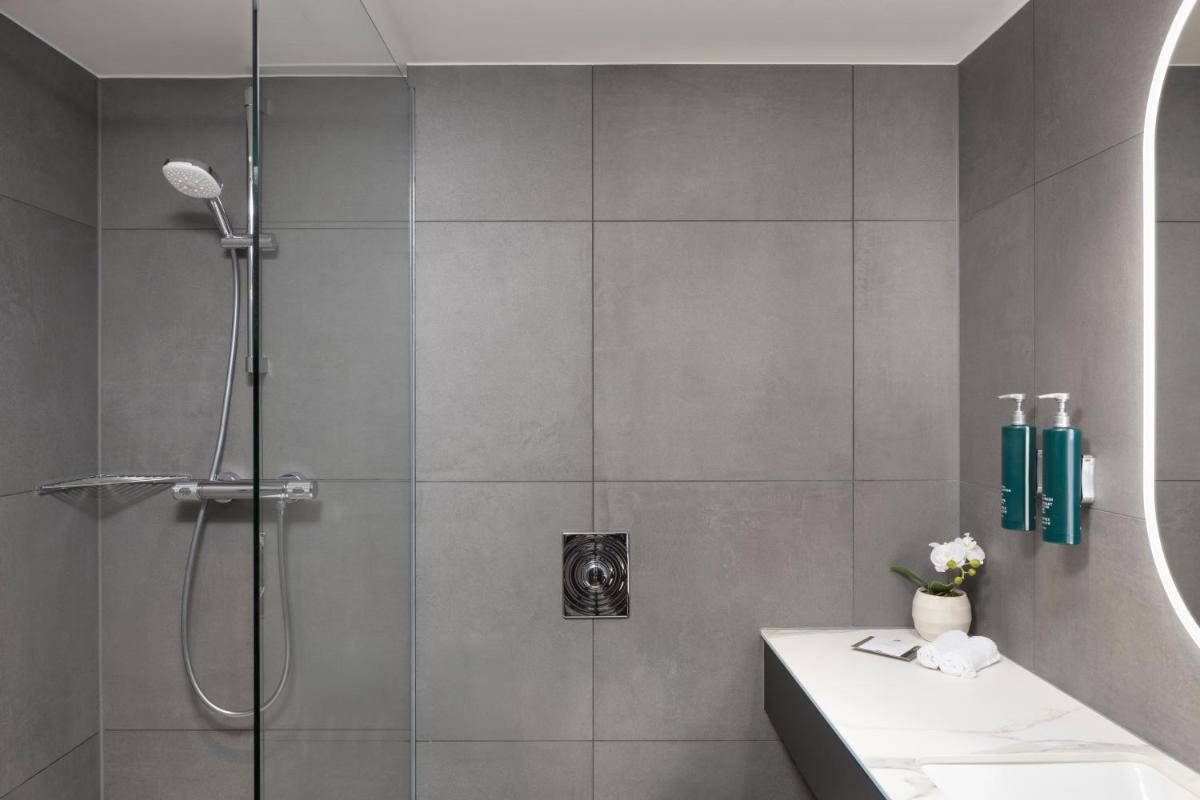 ein Badezimmer mit Dusche und Waschbecken in der Unterkunft Hilton Düsseldorf in Düsseldorf