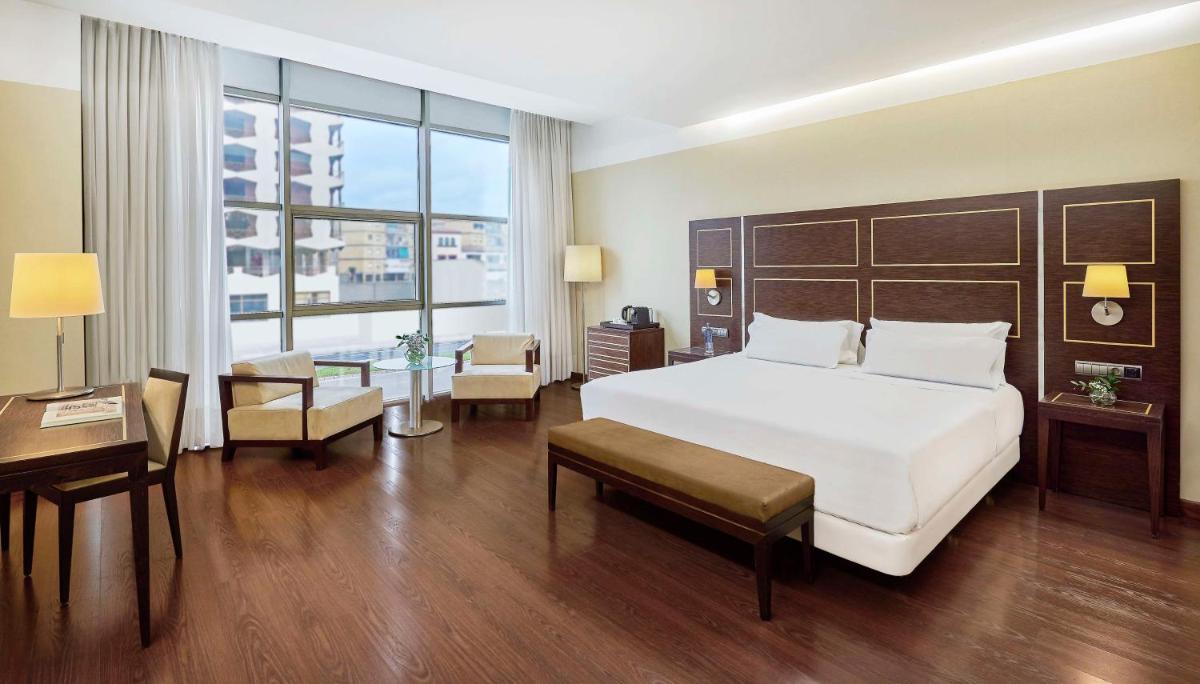 Una habitación de hotel con una cama grande y un escritorio. en NH Gran Hotel Casino de Extremadura, en Badajoz