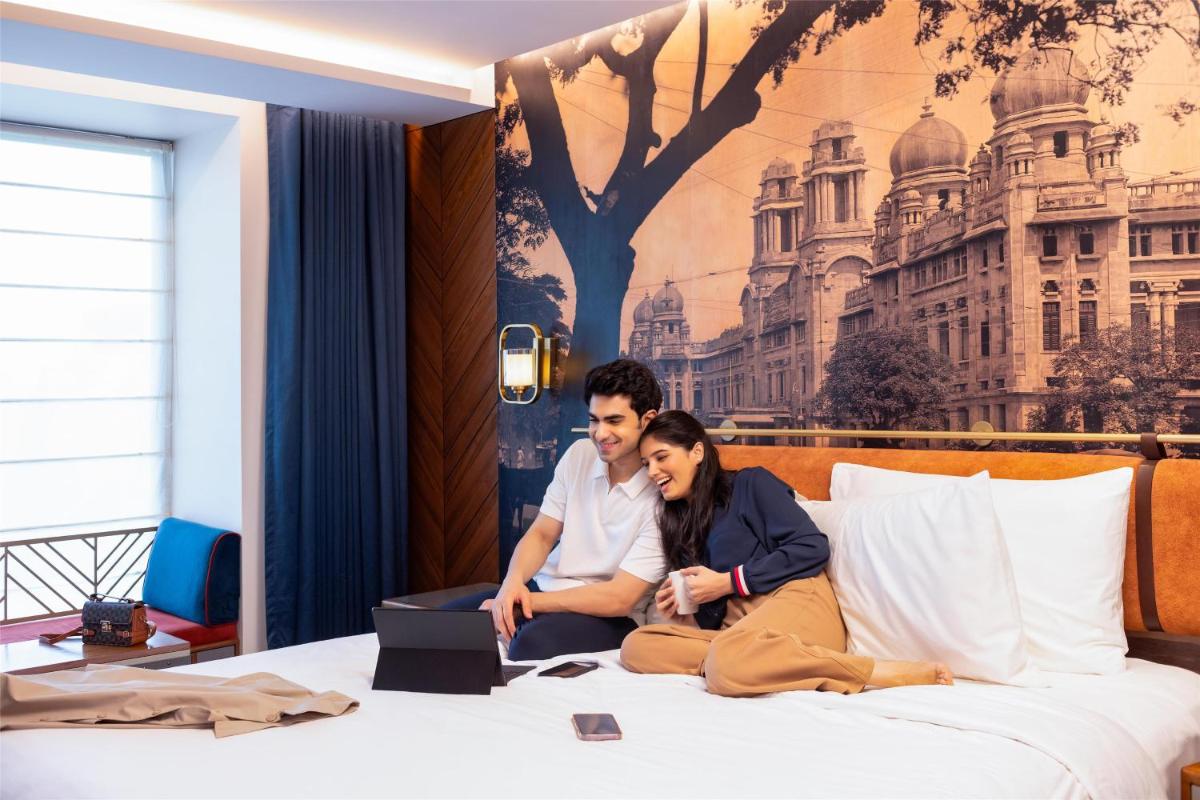 a man and woman sitting on a bed with a laptop at Radisson Blu Hotel & Suites GRT Chennai in Chennai