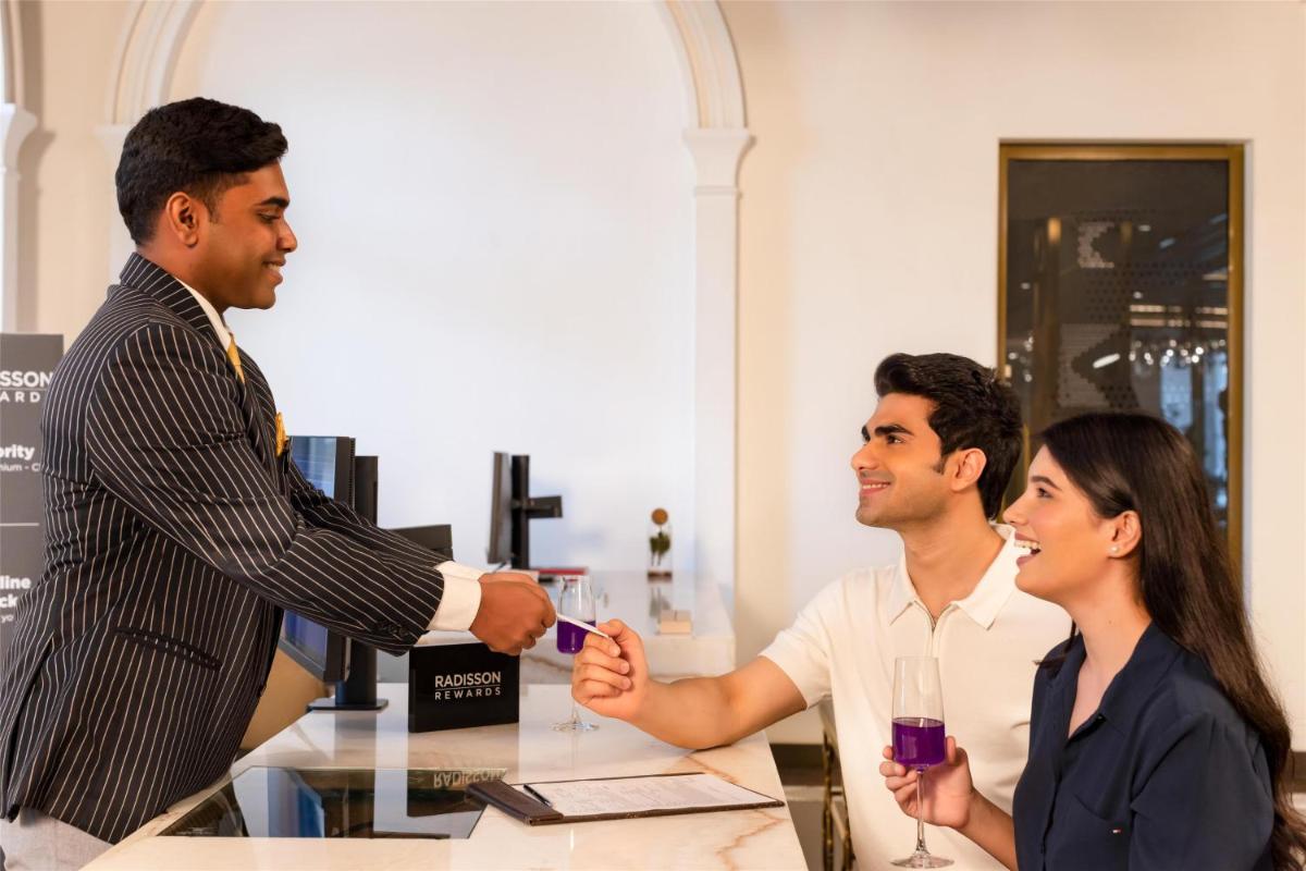 a man shaking hands with two people at a table at Radisson Blu Hotel & Suites GRT Chennai in Chennai