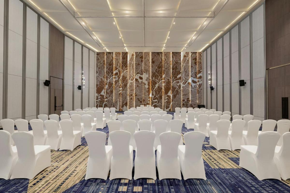 a conference room with white chairs and a stage at Le Meridien Ahmedabad in Ahmedabad