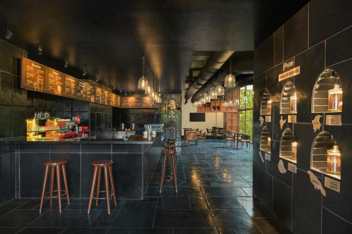 a restaurant with a bar and stools in a room at Le Meridien Ahmedabad in Ahmedabad