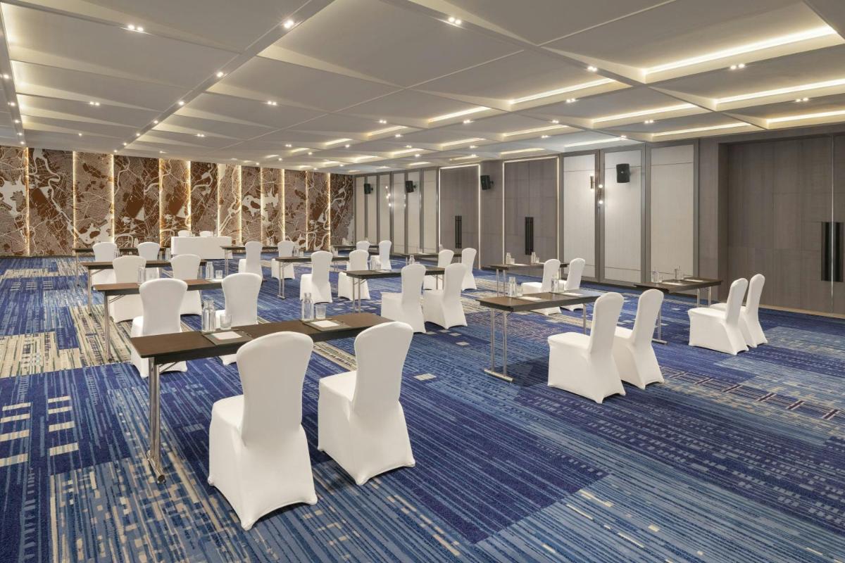 a conference room with tables and white chairs at Le Meridien Ahmedabad in Ahmedabad