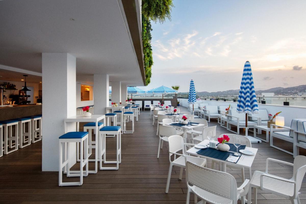 un restaurante con mesas y sillas blancas y vistas al agua en Eurostars Puerto de Ibiza, en Ibiza