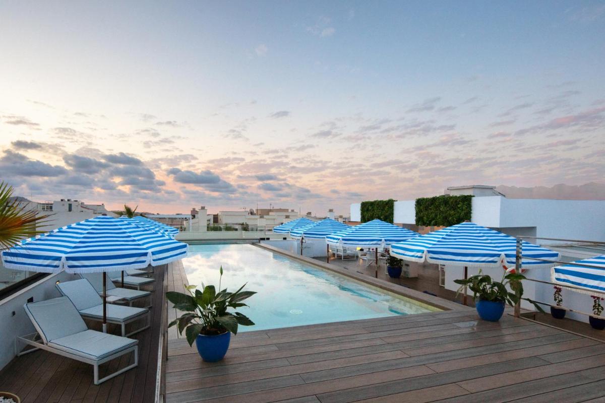 Una piscina con sombrillas azules y blancas en un tejado. en Eurostars Puerto de Ibiza, en Ibiza