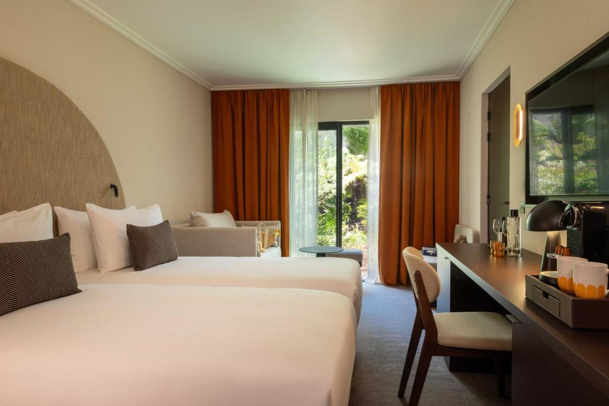une chambre d'hôtel avec deux lits et un bureau dans l'établissement Belinda Hôtel & Spa, à Paris