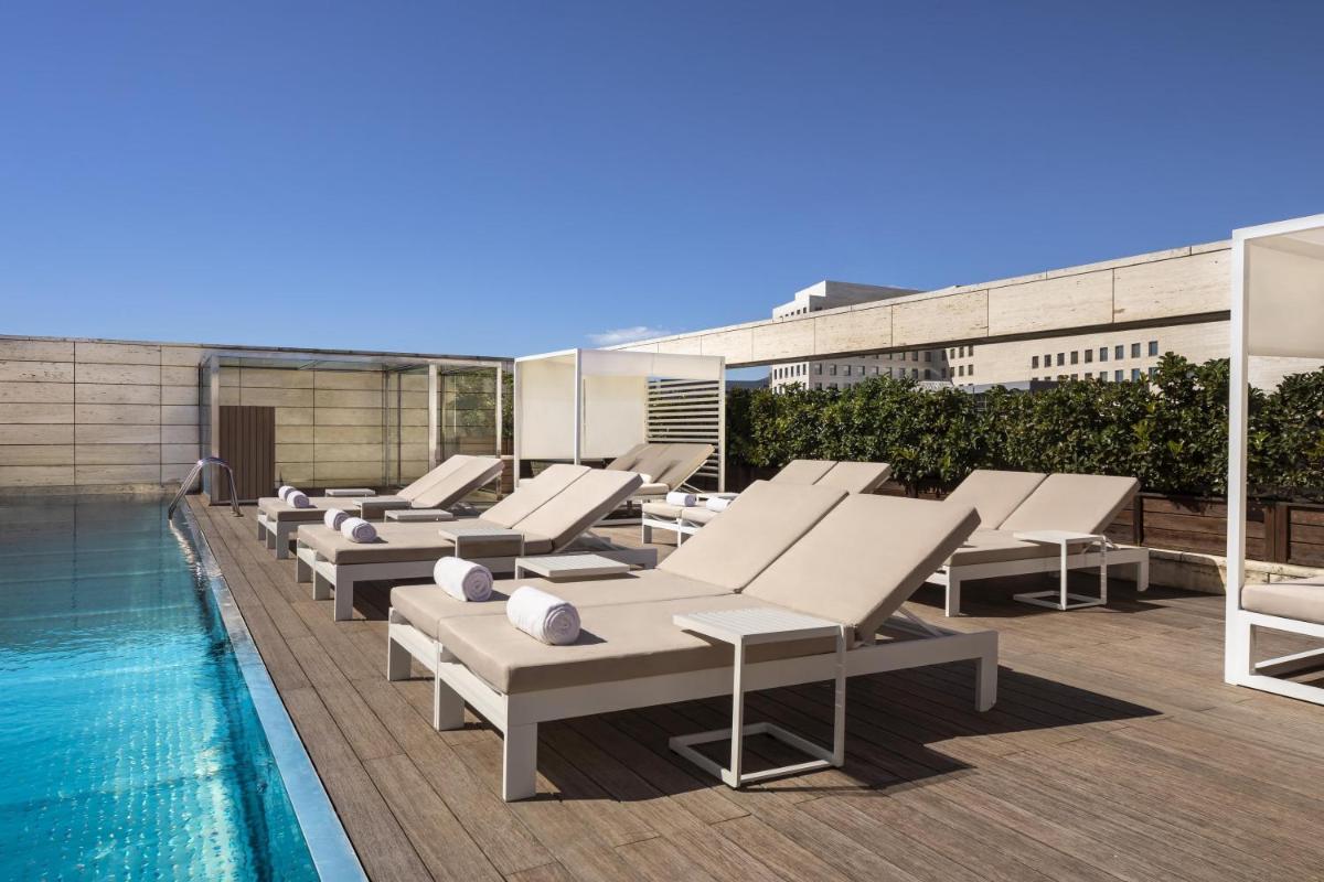 una fila de tumbonas junto a una piscina en NH Collection Barcelona Constanza, en Barcelona