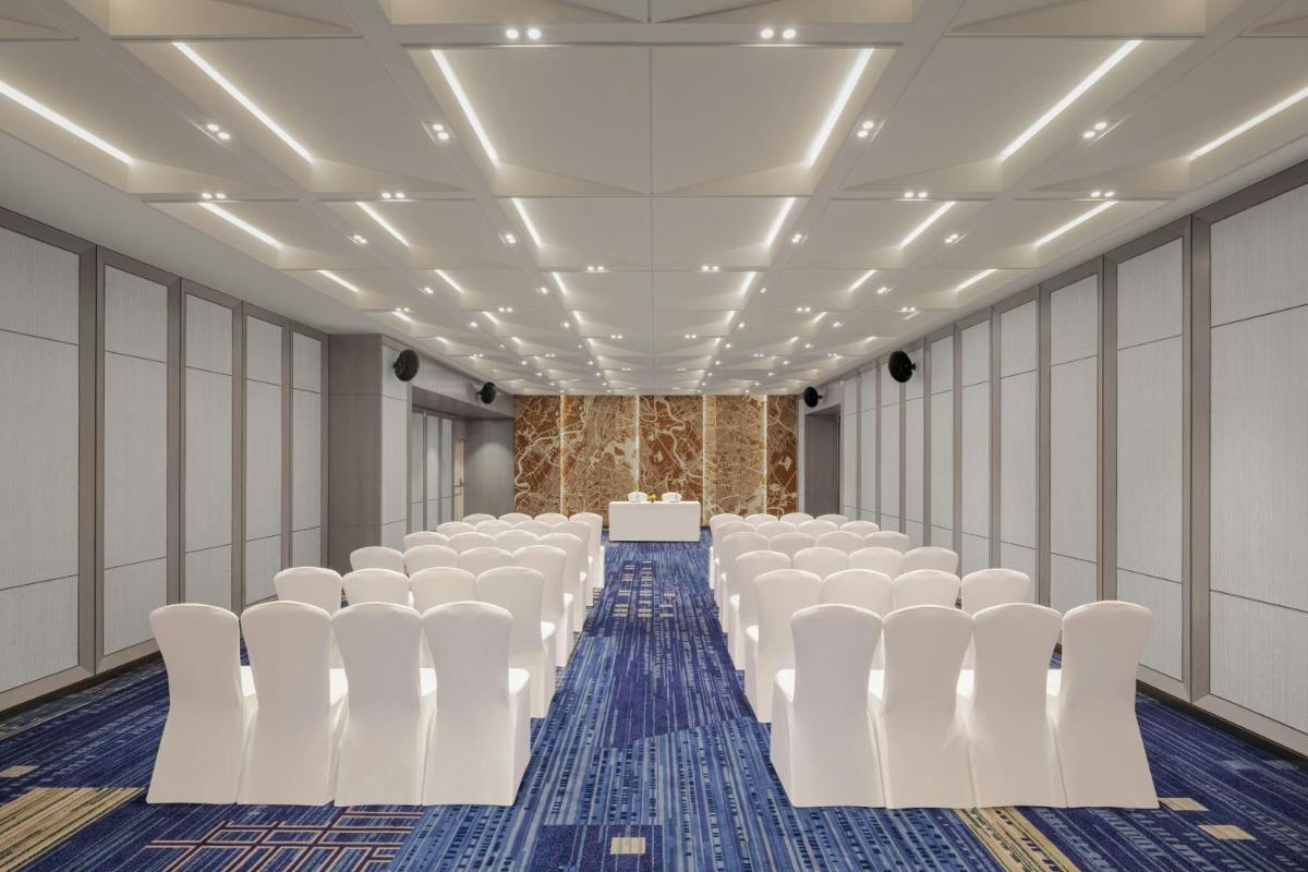 an empty room with white chairs and a table at Le Meridien Ahmedabad in Ahmedabad