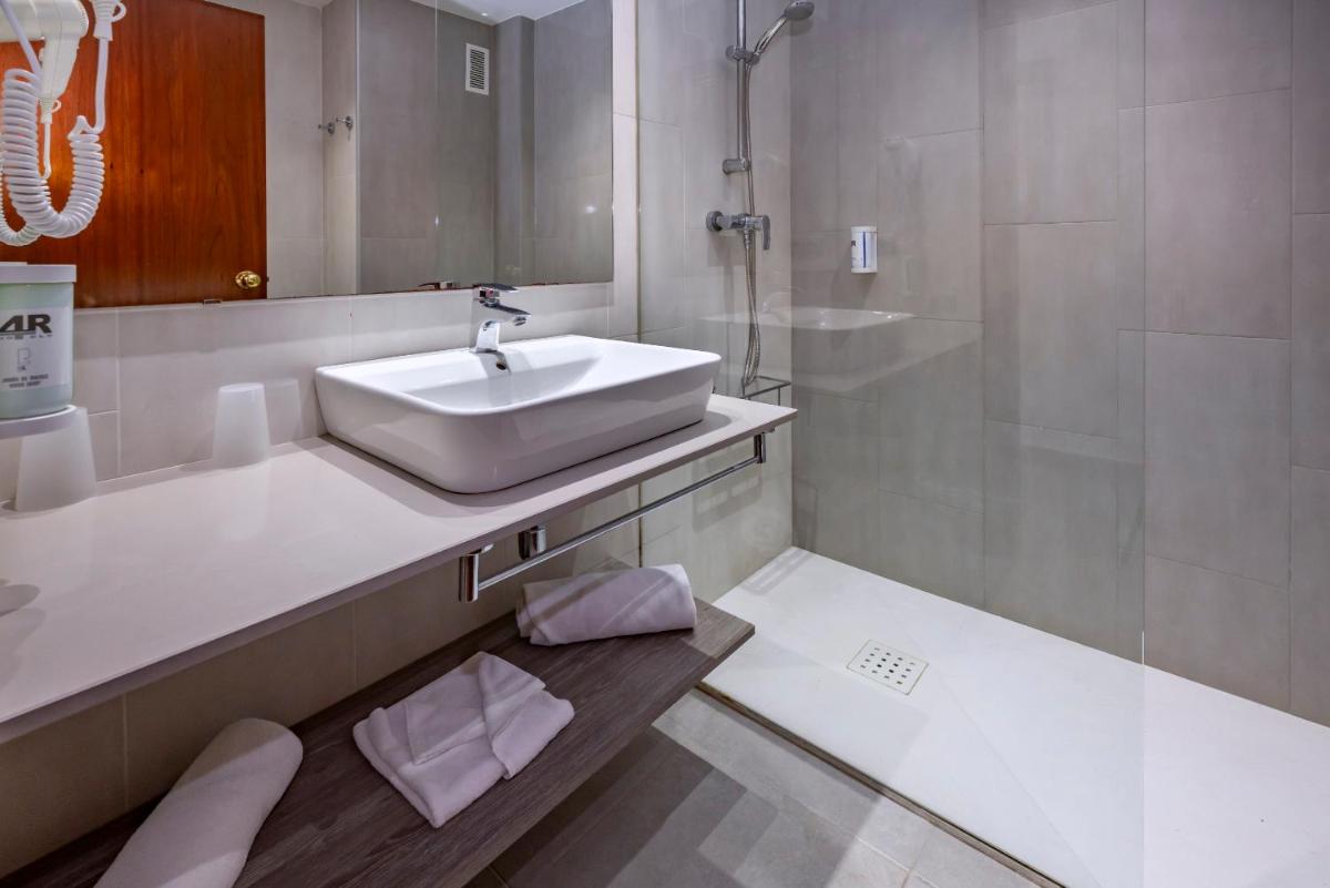 Un baño blanco con lavabo y espejo. en 4R Salou Park Resort I, en Salou