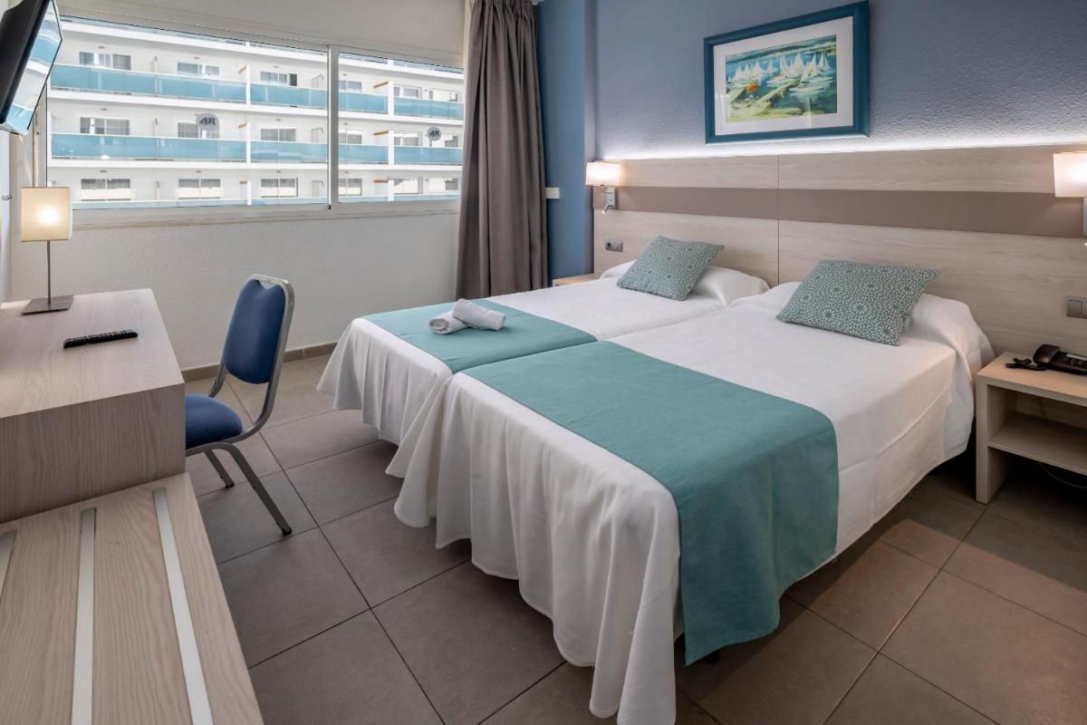 Una habitación de hotel con una cama, un escritorio y una ventana. en 4R Salou Park Resort I, en Salou