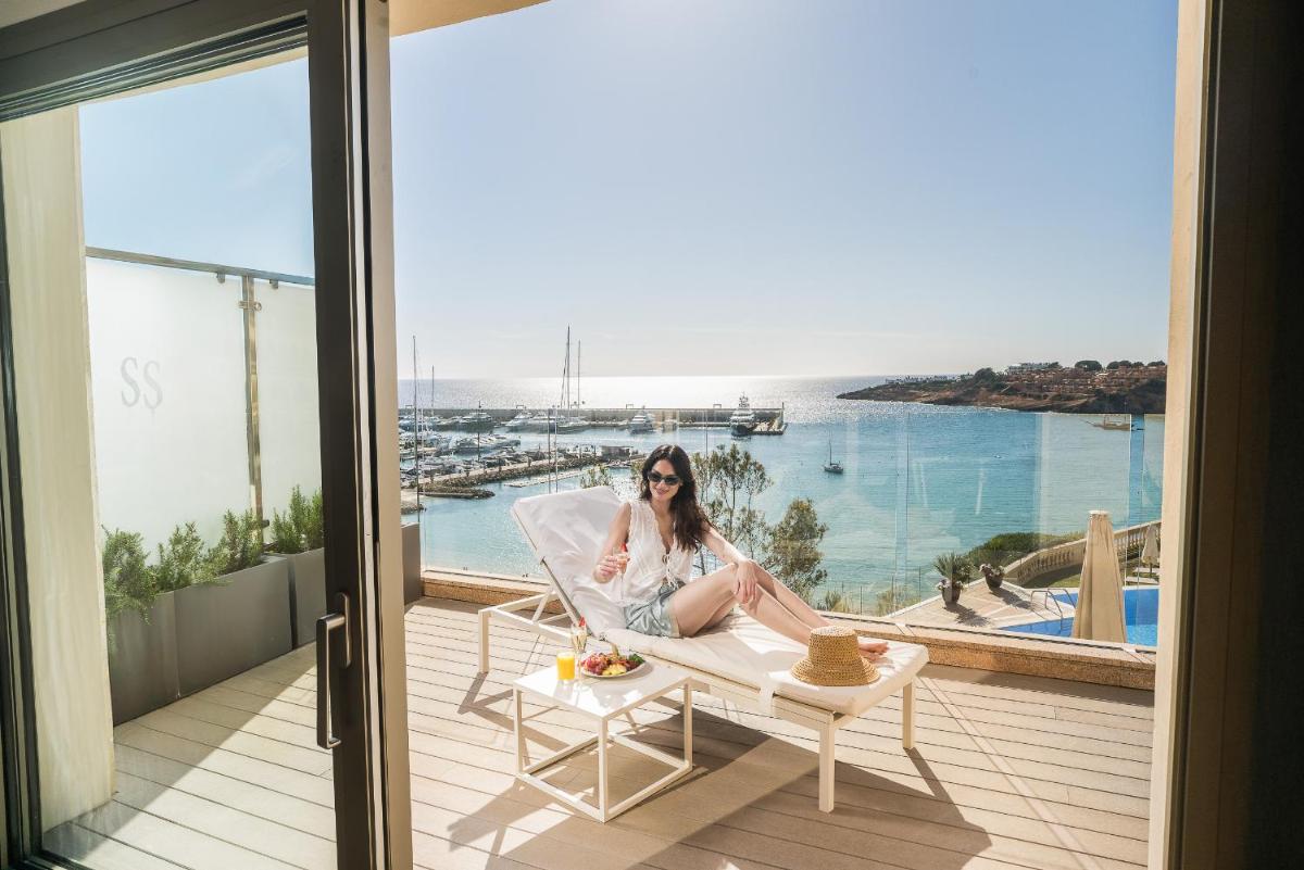 una mujer sentada en una silla en un balcón en Pure Salt Port Adriano - Adults Only, en Santa Ponsa