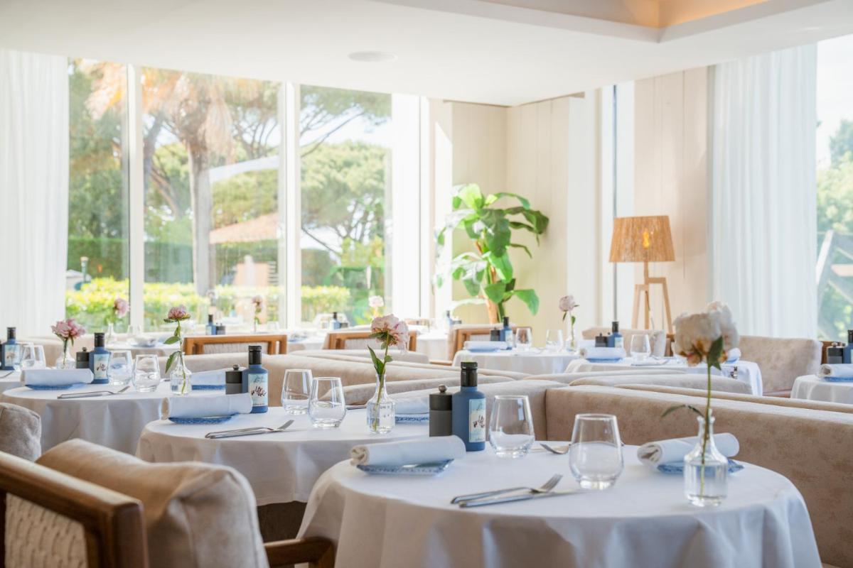 un restaurant avec des tables et des chaises blanches et des fenêtres dans l'établissement Kube Saint-Tropez, à Saint-Tropez