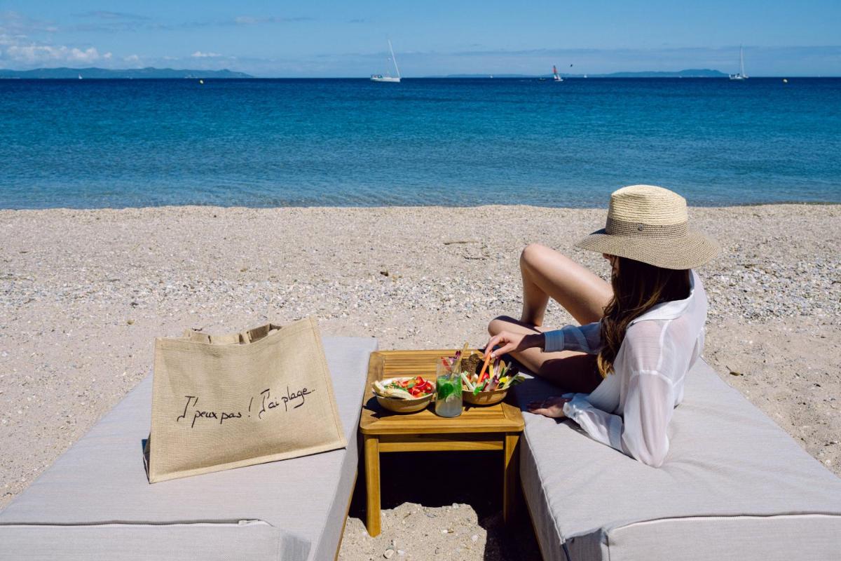 une femme assise sur la plage avec un plateau de nourriture dans l'établissement Le Hameau Des Pesquiers Ecolodge & Spa, Curio Collection By Hilton, à Hyères