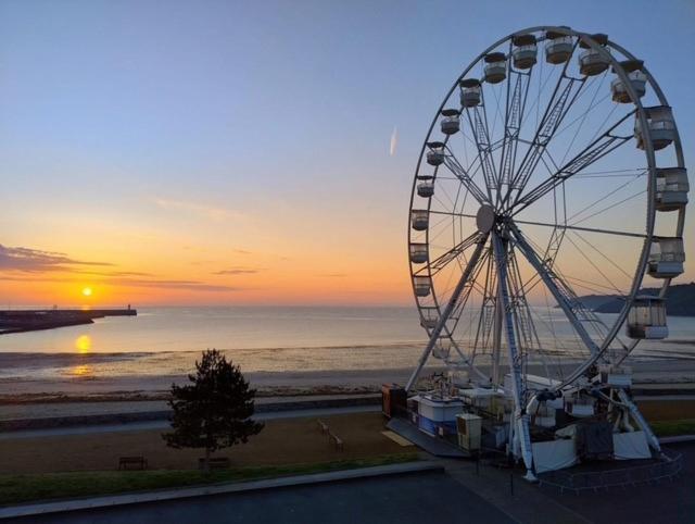 une grande roue devant une plage au coucher du soleil dans l'établissement Brit Hotel Le Galion & Spa, à Binic