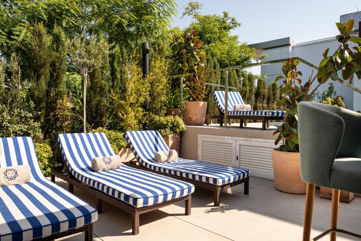 un patio con plantas y sillas azules y blancas en Cavalta Boutique Hotel - Small Luxury Hotels, en Sevilla