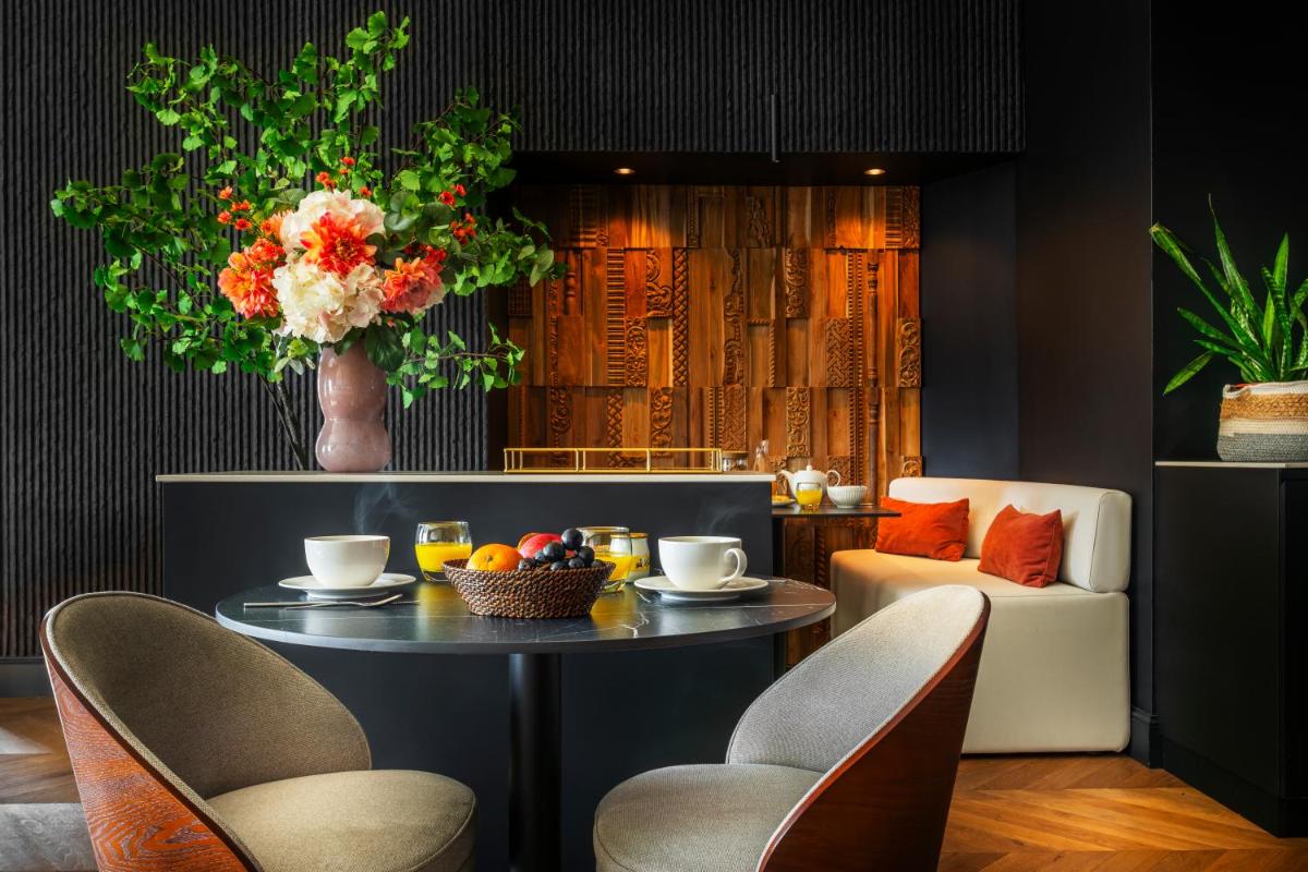 - une salle à manger avec une table, des chaises et un bol de fruits dans l'établissement Hotel & Spa Les Roches Noires, à Les Sables-dʼOlonne