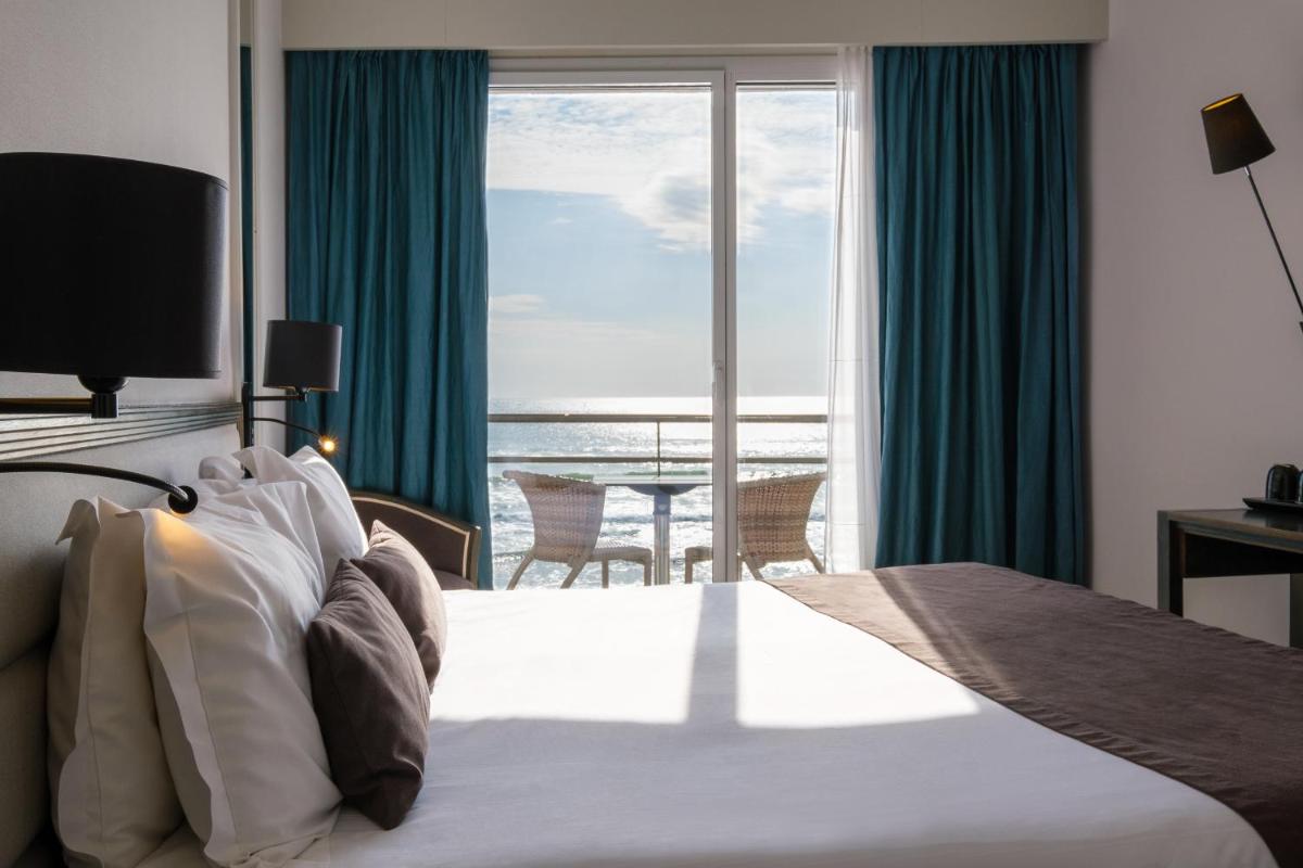 une chambre avec un lit avec vue sur l'océan dans l'établissement Hotel & Spa Les Roches Noires, à Les Sables-dʼOlonne
