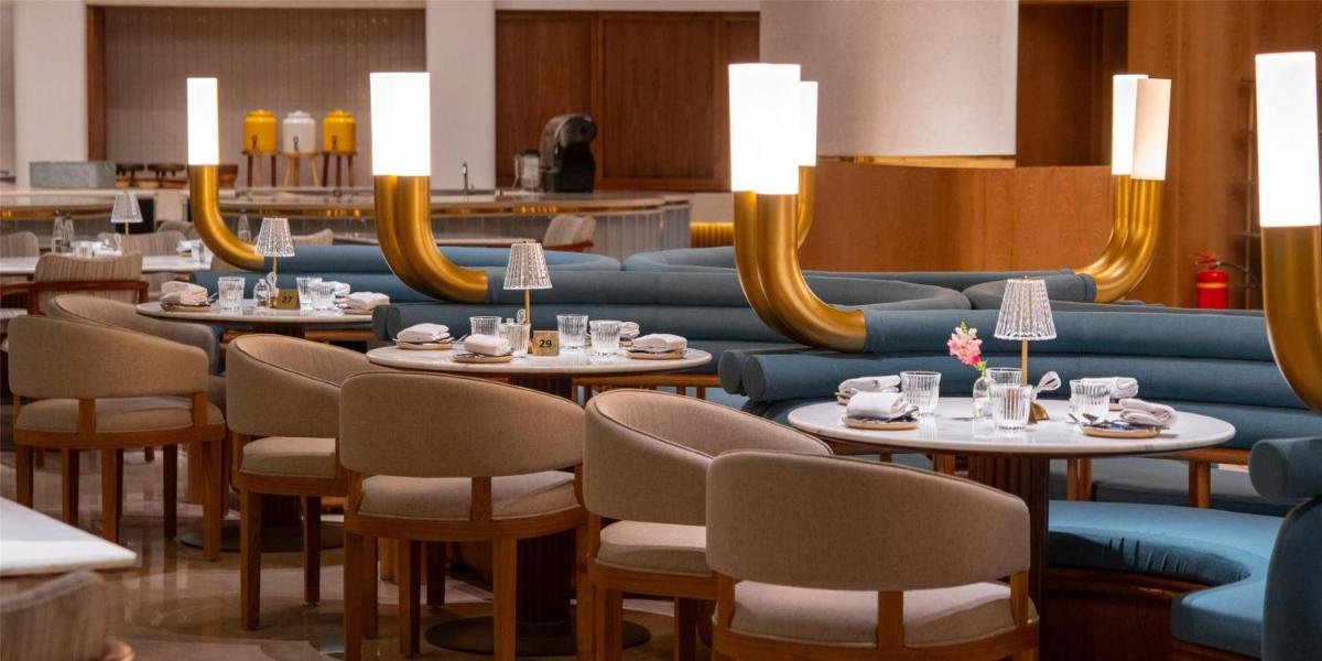 a dining room with tables and chairs and mirrors at Hilton Bangalore Embassy GolfLinks in Bengaluru