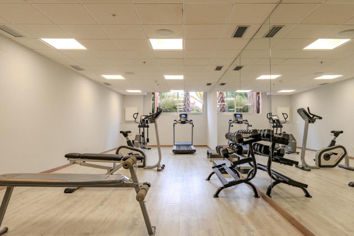 un gimnasio con varias cintas de correr y máquinas elípticas en Tarifa Lances by QHotels, en Tarifa