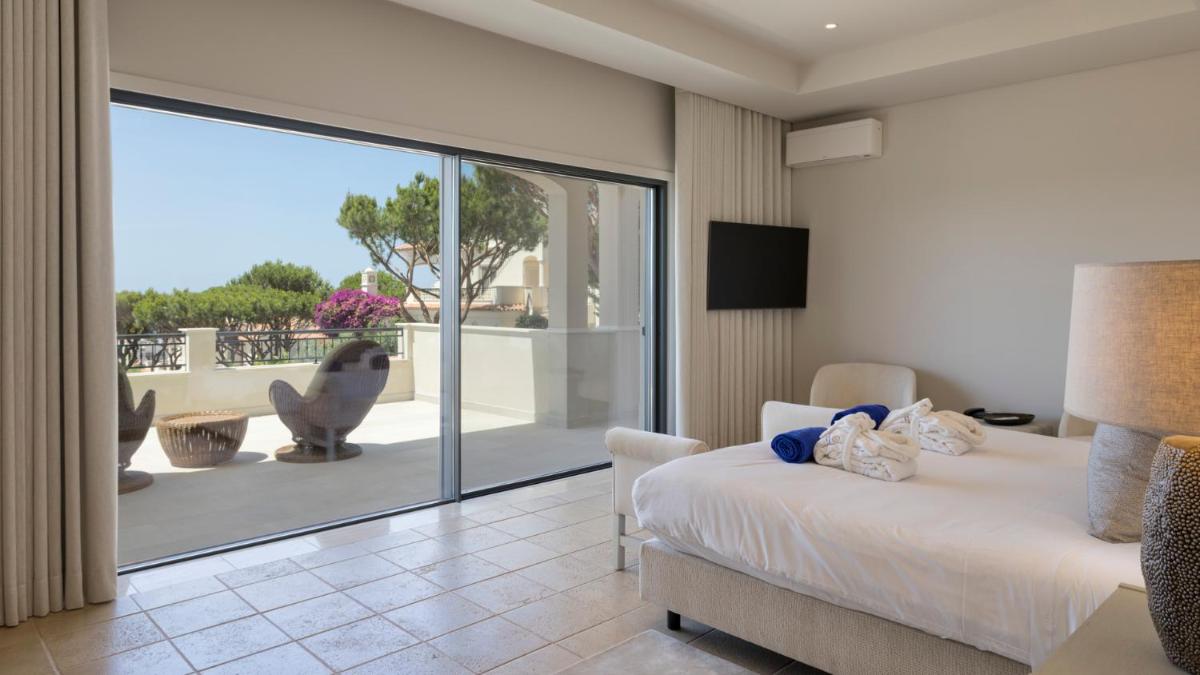 um quarto com uma cama e uma porta de vidro deslizante em Dunas Douradas Beach Club no Vale do Lobo