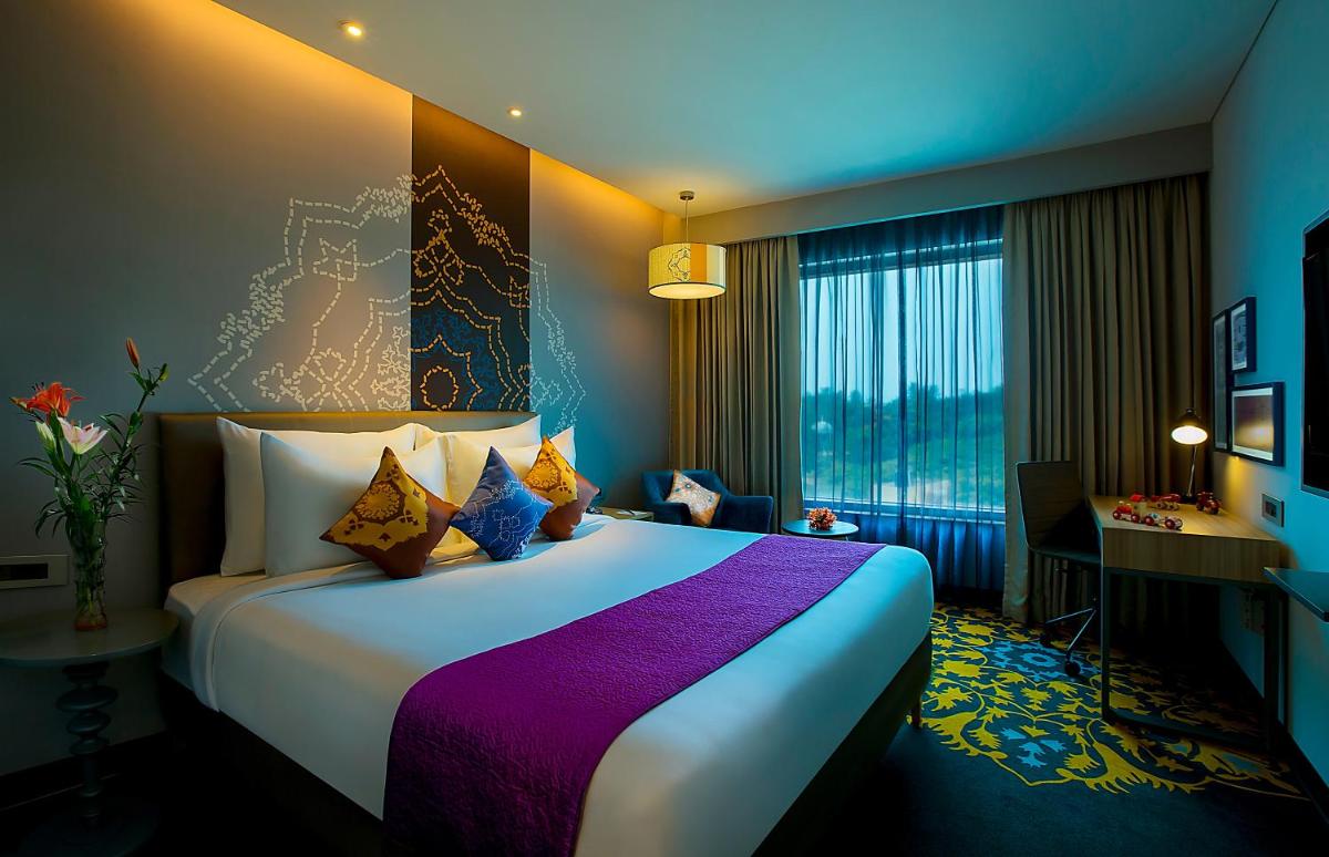 a hotel room with a large bed and a desk at Grand Mercure Mysore - An Accor Brand in Mysore