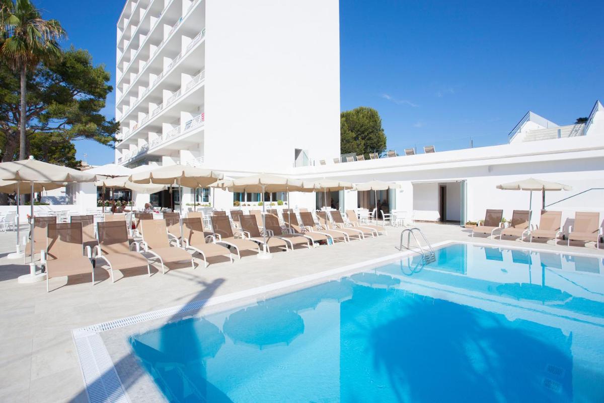 Una piscina con tumbonas y un hotel. en Grupotel Farrutx, en Can Picafort