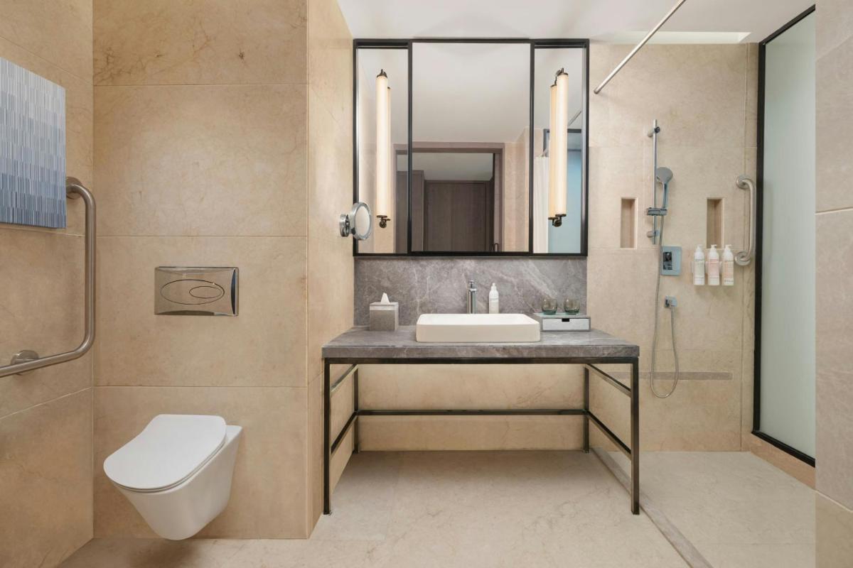 a bathroom with a sink and a toilet and a mirror at Le Meridien Ahmedabad in Ahmedabad