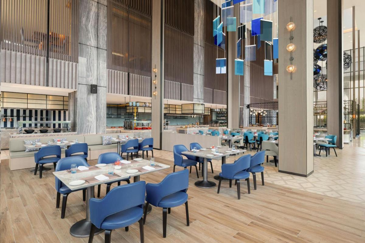 a dining room with tables and blue chairs at Le Meridien Ahmedabad in Ahmedabad