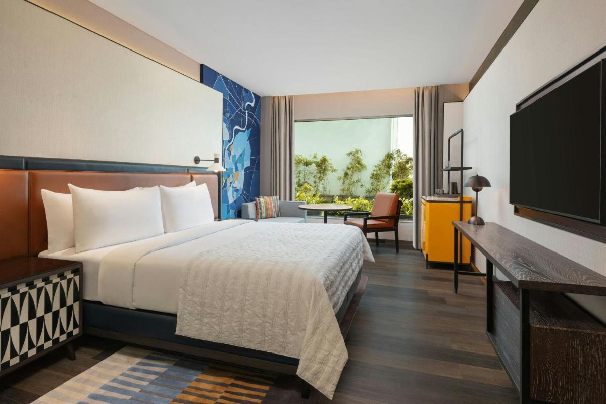 a hotel room with a bed and a flat screen tv at Le Meridien Ahmedabad in Ahmedabad