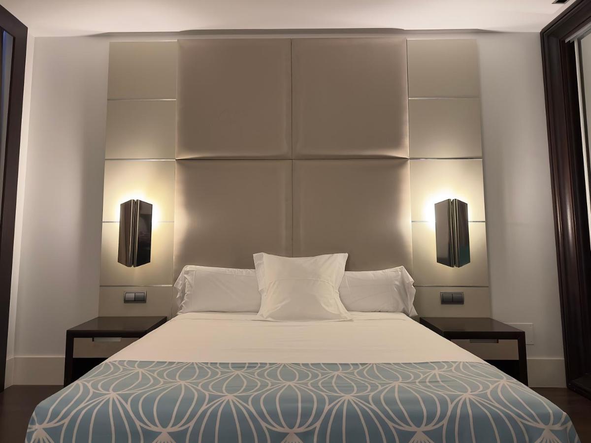 Un dormitorio con una cama grande con dos lámparas. en Hotel Palacio Albacete & SPA, en Albacete