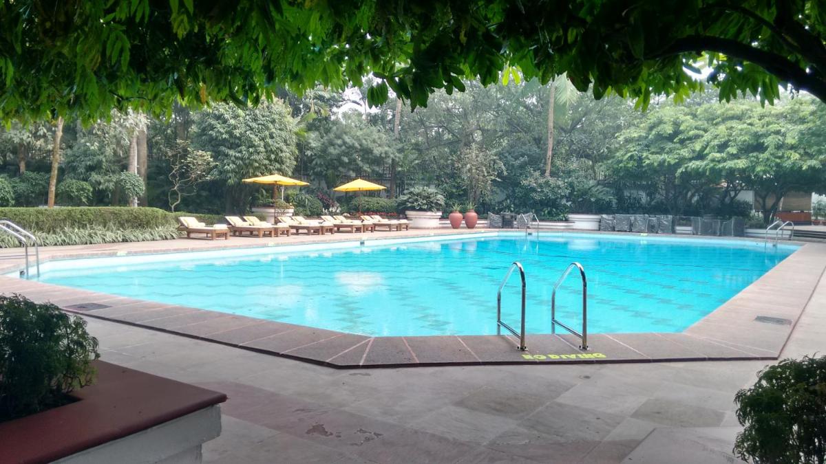 a large swimming pool with chairs and umbrellas at Taj Bengal in Kolkata