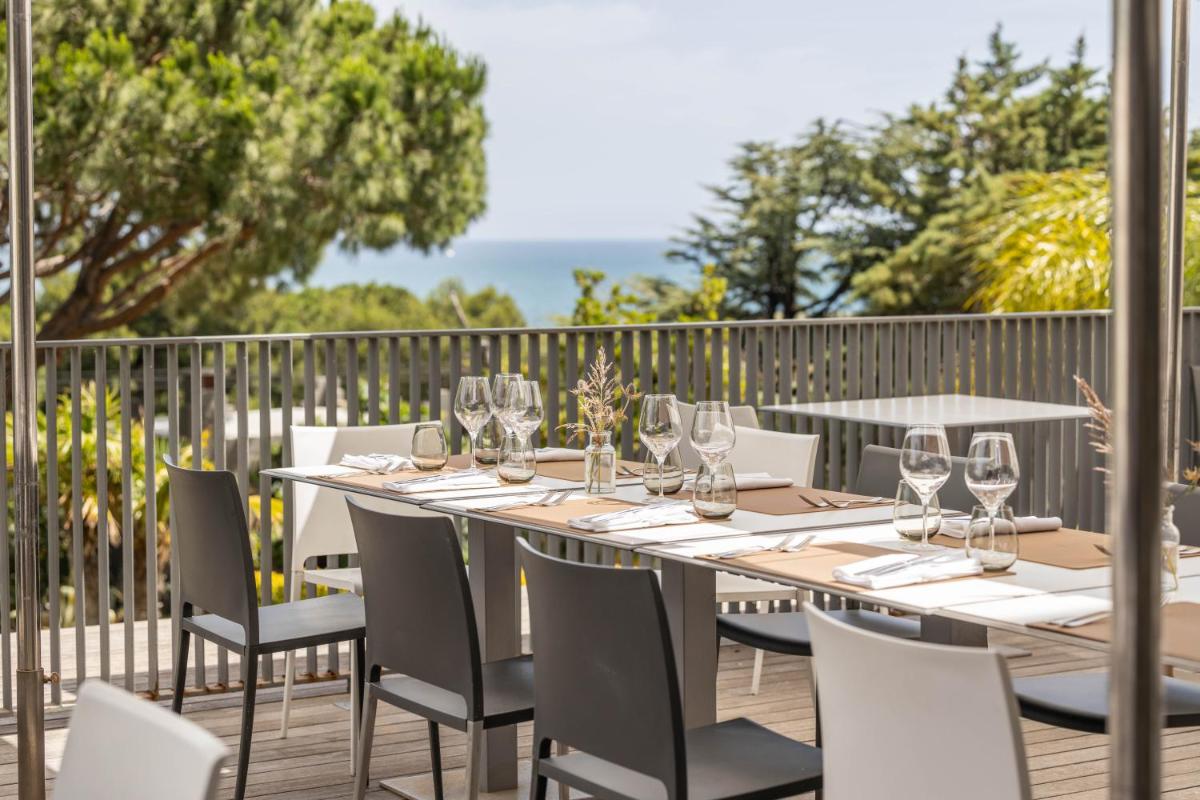 une table avec des verres à vin et des chaises sur une terrasse dans l'établissement Grand Hotel Du Golfe - Spa & Restaurant, à Collioure
