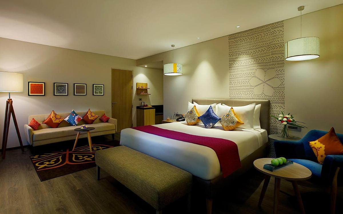 a hotel room with a large bed and a couch at Grand Mercure Mysore - An Accor Brand in Mysore