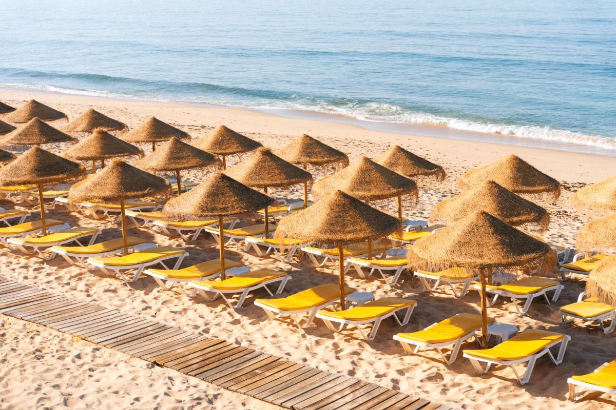 um grupo de guarda-sóis e cadeiras numa praia em Eden Villas & Apartments em Albufeira