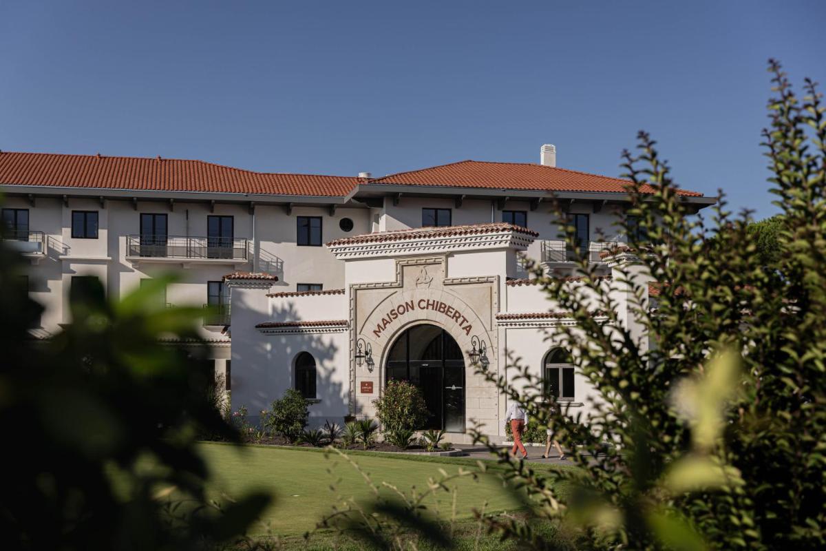 un grand bâtiment blanc avec un portail dans une cour dans l'établissement Hôtel Maison Chiberta, à Anglet