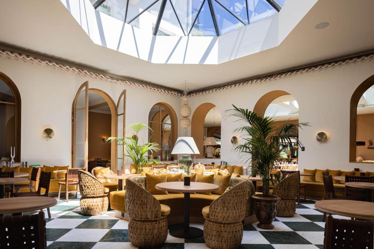 Le hall de l'hôtel est doté de tables, de chaises et d'une lucarne. dans l'établissement Hôtel Maison Chiberta, à Anglet