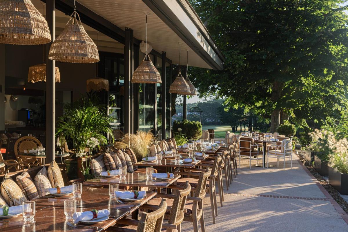 un restaurant avec des tables et des chaises en bois et des lumières dans l'établissement Hôtel Maison Chiberta, à Anglet