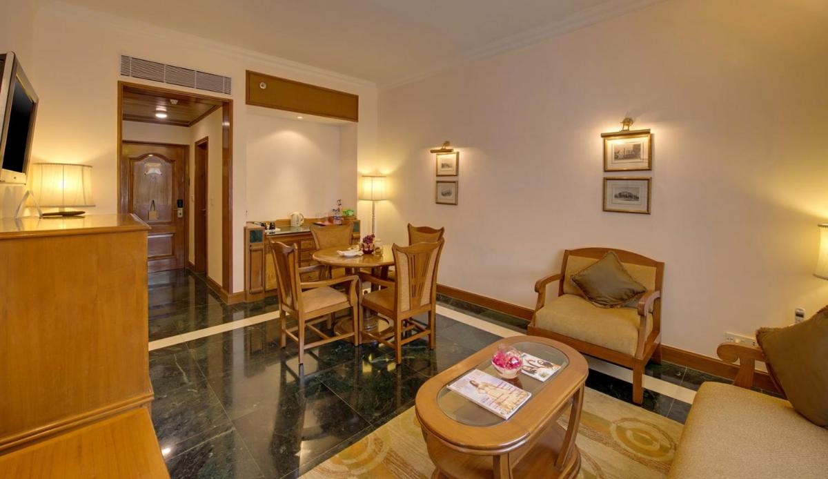 a living room with a table and chairs at The Ummed Ahmedabad Airport in Ahmedabad