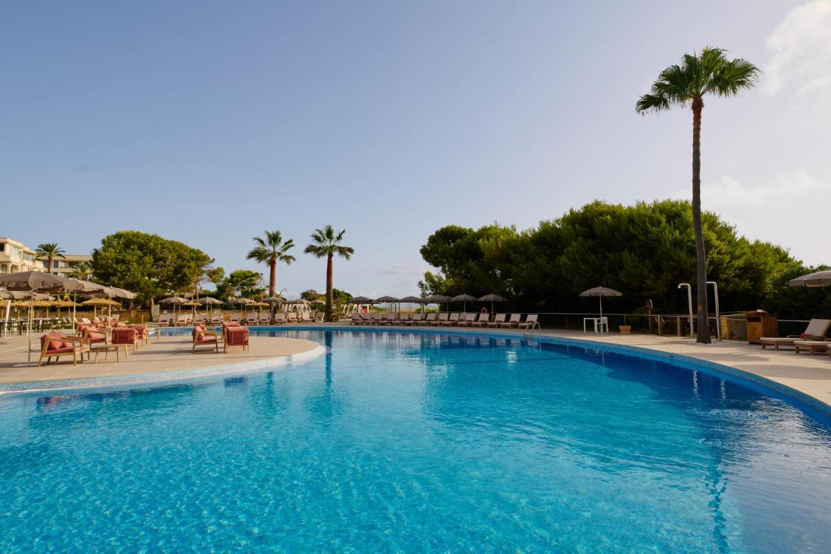 Una gran piscina con sillas y sombrillas en un resort. en Sarena de Muro Resort Mallorca, part of Destination by Hyatt, en Playa de Muro