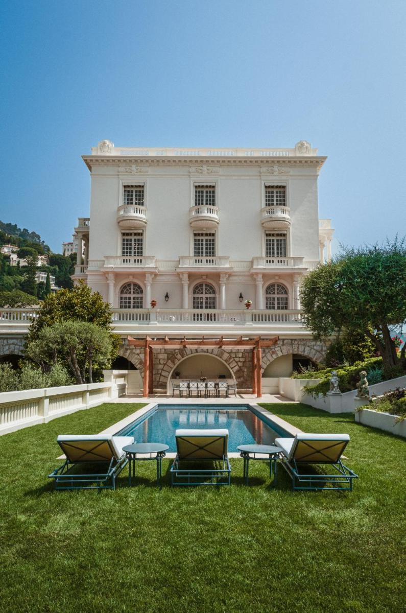 un grand bâtiment avec une piscine dans la cour dans l'établissement Monte-Carlo Beach, à Roquebrune-Cap-Martin