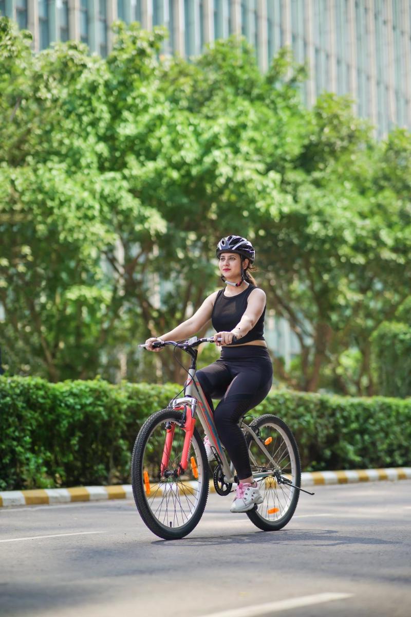 a woman riding a bike down a street at The Leela Ambience Gurugram Hotel & Residences - The Luxury Urban Sanctuary in Gurgaon