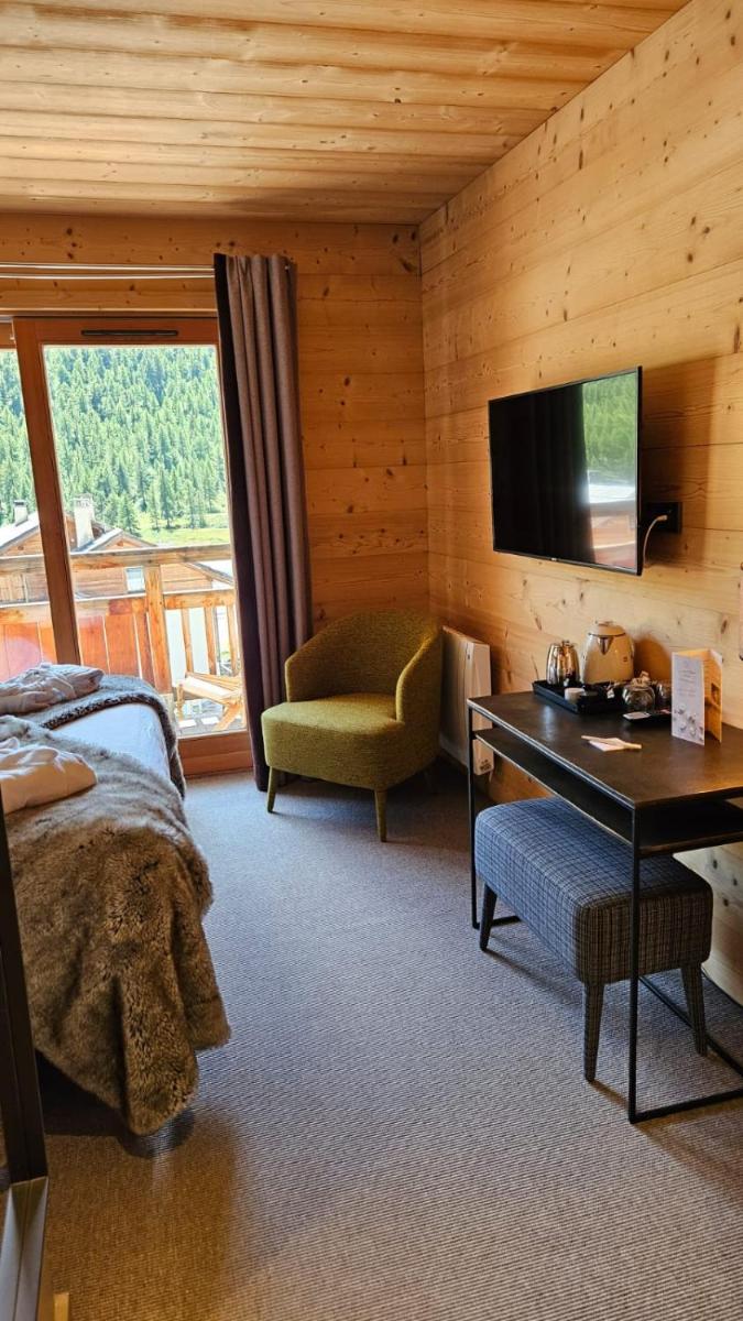 une chambre avec un lit, un bureau et une télévision dans l'établissement Le Chalet Blanc Hôtel & Spa, à Montgenèvre