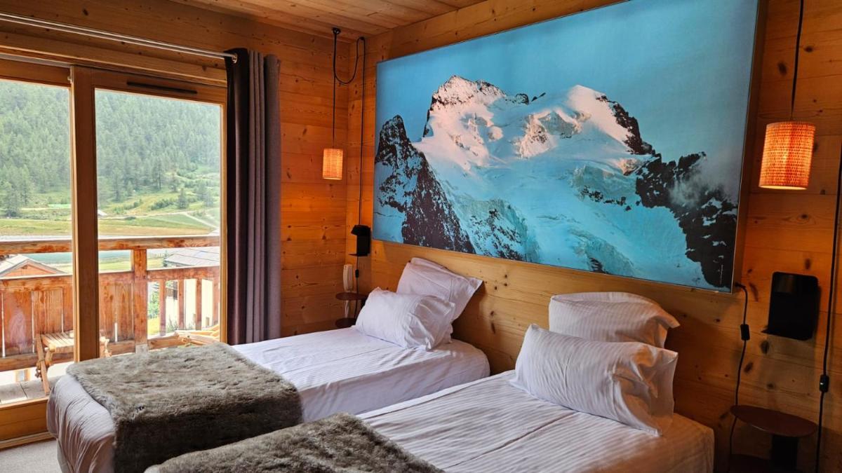 une chambre avec deux lits et une grande fenêtre dans l'établissement Le Chalet Blanc Hôtel & Spa, à Montgenèvre