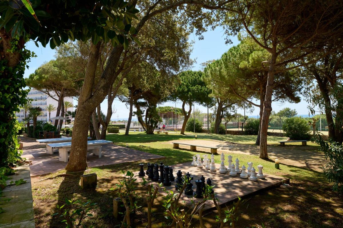 Un tablero de ajedrez en un parque con bancos y árboles. en Alua Illa de Menorca, en S'Algar 48 fotos más